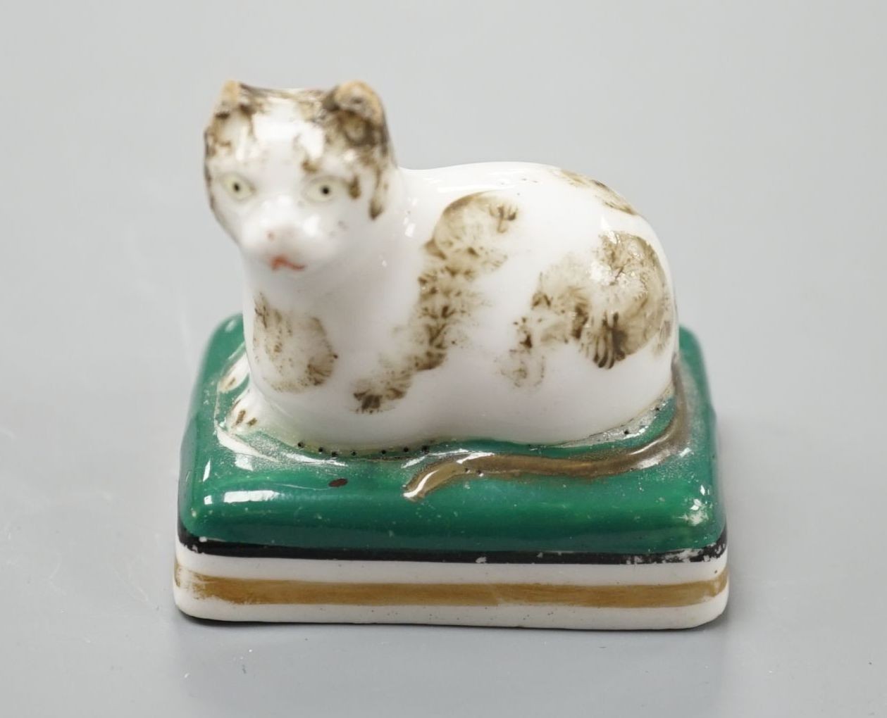 A rare English porcelain model of a recumbent cat, probably Derby c.1830, 4.5 cm long, Cf. Dennis G.Rice Cats in English porcelain, colour plate 24., Provenance: Dennis G.Rice collection